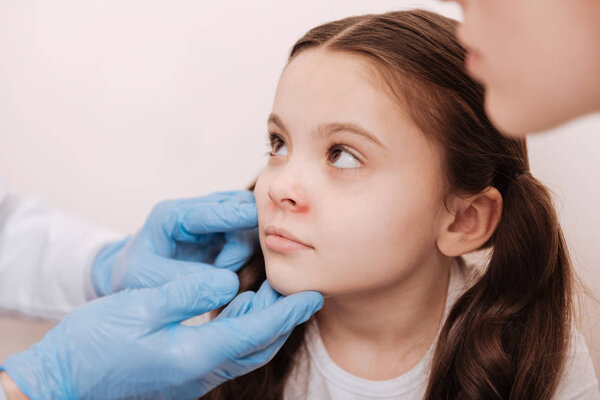 Nice sad child visiting dermatologist with her mom