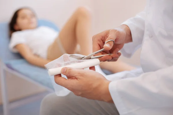 Bom médico masculino cortando uma bandagem — Fotografia de Stock