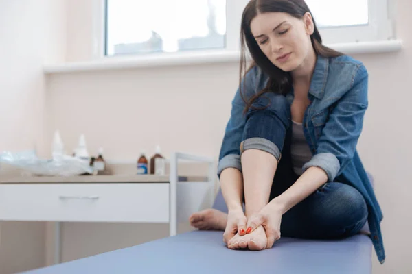 Alegre mujer malhumorada sosteniendo sus pies — Foto de Stock