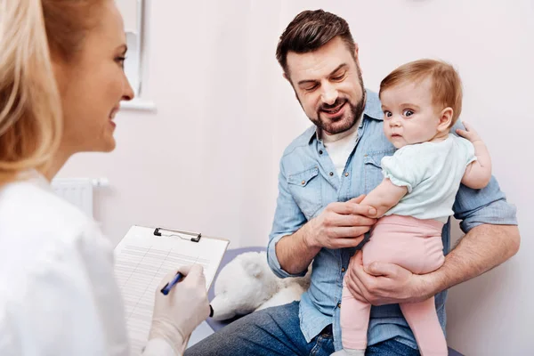 Pediatra sonriente haciendo las notas necesarias — Foto de Stock