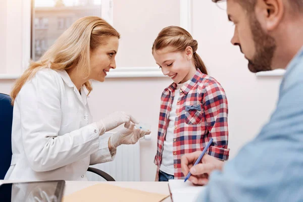 Blij weinig vrouwelijke patiënt handen van kinderarts kijken — Stockfoto