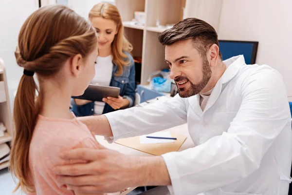 Atento pediatra joven examinando a su paciente — Foto de Stock