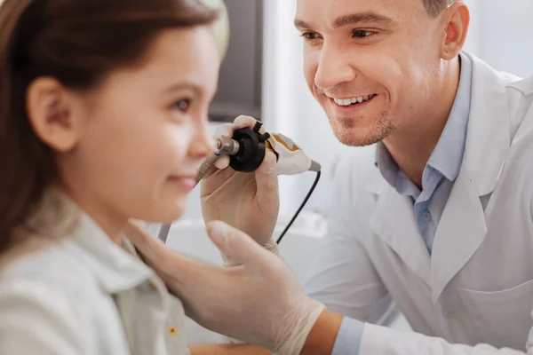 Trabalhador médico encantado positivo que trata a orelha do paciente — Fotografia de Stock