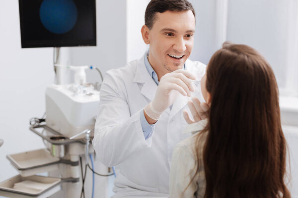 Smiling otolaryngologist checking throat of his patient