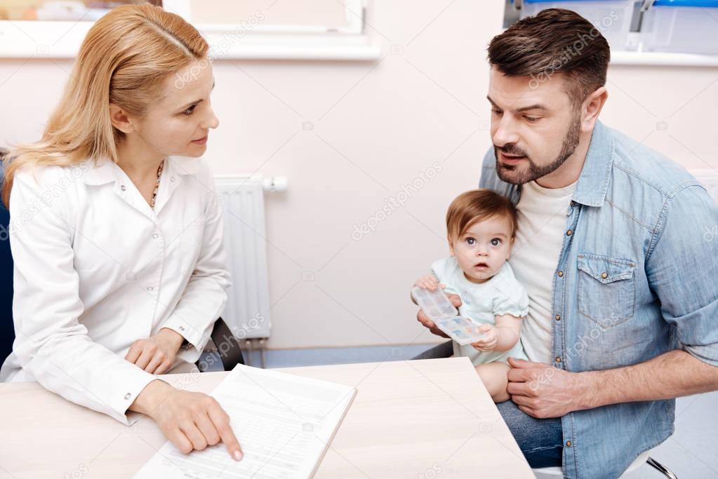 Attentive father sitting opposite family doctor