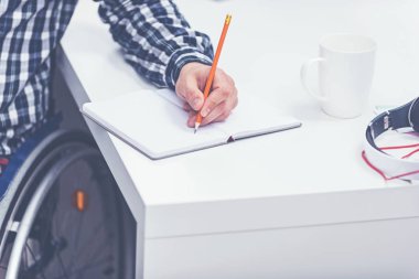 Tekerlekli sandalyede oturan ve notlar kapalı genç adam