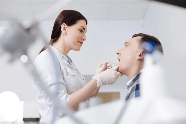 Médico competente olhando para a boca de seu paciente — Fotografia de Stock