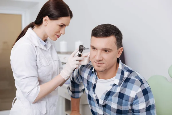 Serious otolaryngologist examining ear of male patient — Stock Photo, Image