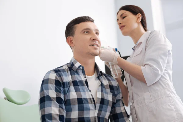 Ernstige arts blozen uit oor van mannelijke patiënt — Stockfoto
