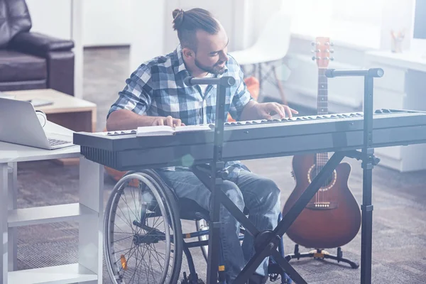 Hombre inspirado en la silla de ruedas tocando instrumentos musicales en interiores —  Fotos de Stock