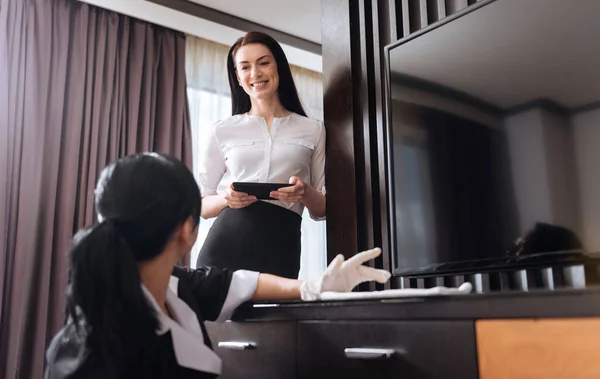 Aantrekkelijke vrolijke vrouw kijken naar de hotel meid — Stockfoto