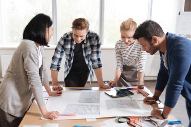 Genç mühendisler çizimlere bakarak çalışkan