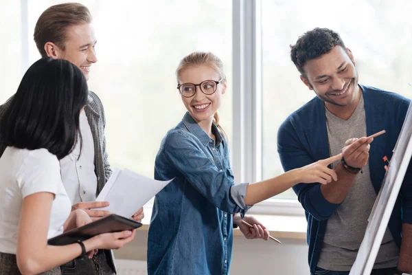 Agradable mujer alegre de pie con sus colegas — Foto de Stock