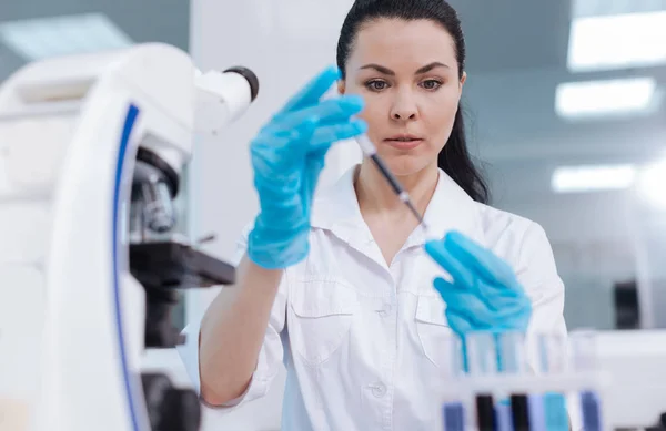 Attentive female person taking reagent into medicine dropper