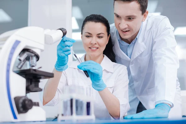 Delighted female researcher looking at test-tube