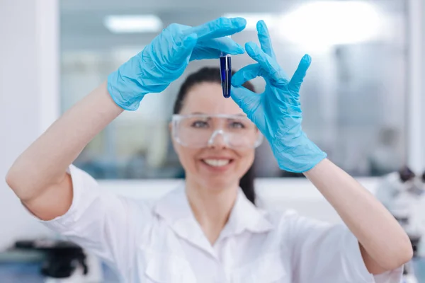 Cientista feminina sorridente olhando para tubo de ensaio — Fotografia de Stock