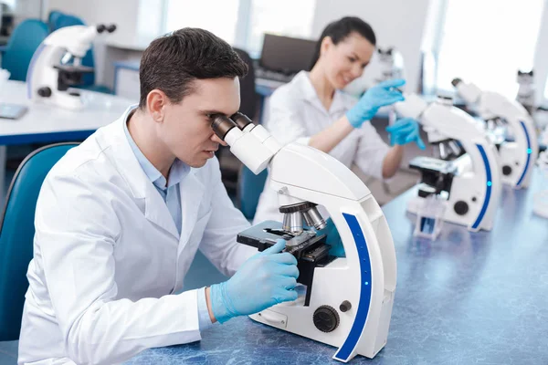 Very attentive lab assistant working with microscope — Stock Photo, Image