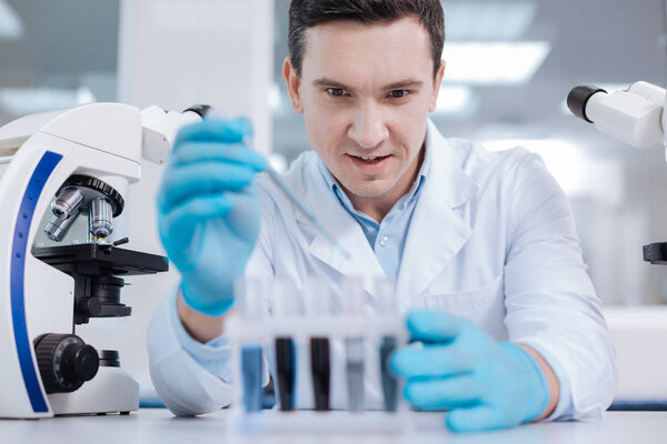 Delighted male person looking at test-tubes