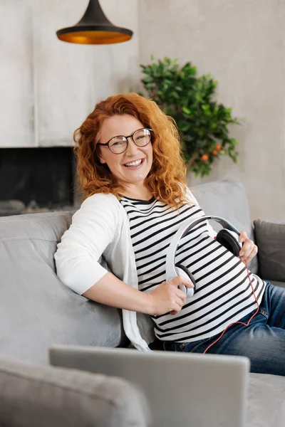 Aufgeregte werdende Mutter mit Kopfhörern auf dem Bauch — Stockfoto