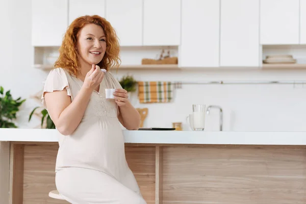 Беременная женщина, наслаждающаяся вкусным йогуртом — стоковое фото