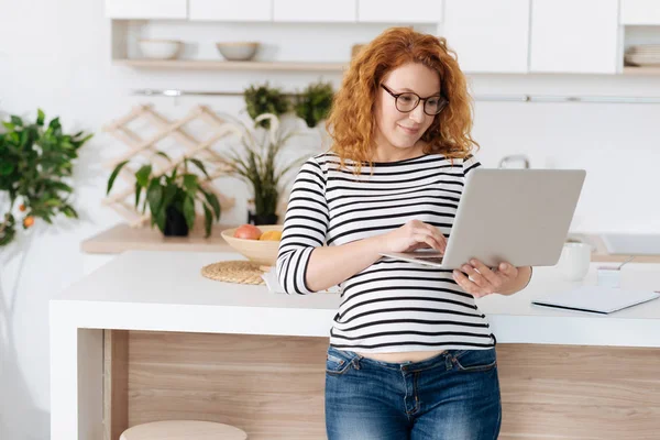 Улыбающиеся беременные женщины смотрят на ноутбук и работают — стоковое фото