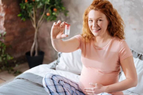 Блестящая будущая мать держит бутылку с таблетками — стоковое фото
