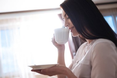 bir fincan tutarak ve bir yudum alarak kadın