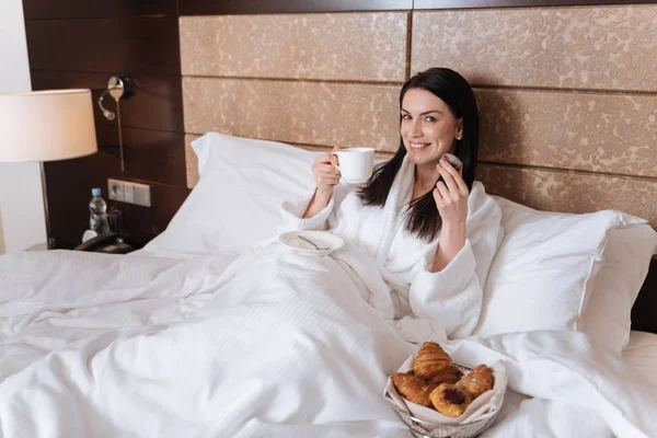 Nő étkezési croissant-t tartalmaz az ágyban — Stock Fotó