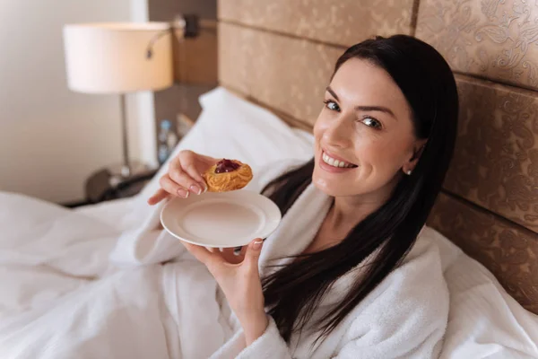 Mujer comiendo un pastel en la cama — Foto de Stock