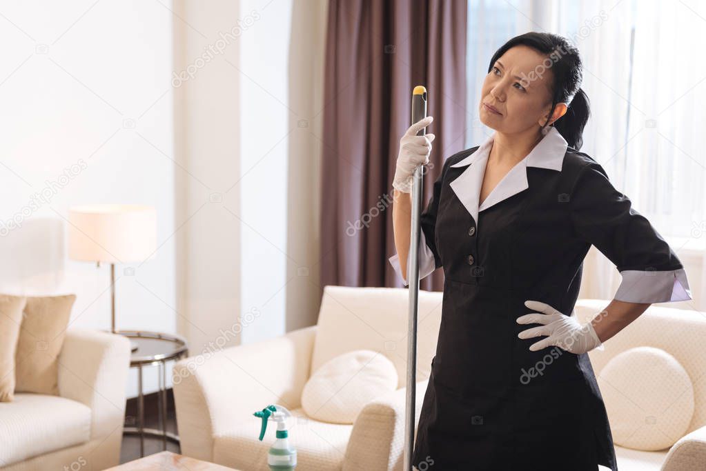 Nice thoughtful woman holding a mop