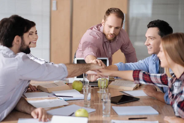 Gruppe positiver Arbeiter, die am Arbeitsplatz die Hände zusammenhalten — Stockfoto