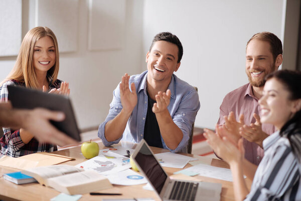 Group of delighted professionals clasping hands