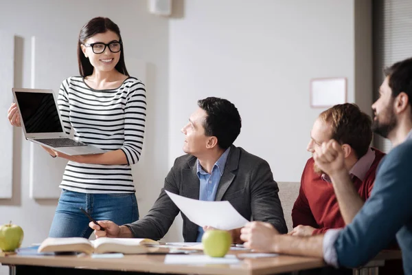 Mujer positiva y encantada mostrando su presentación a sus colegas —  Fotos de Stock