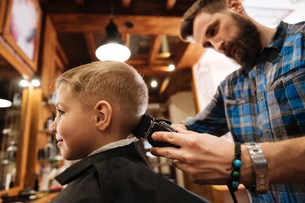 Cabeleireiro barbudo fazendo o corte de cabelo para a criança — Fotografia de Stock