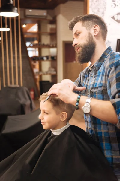 Sério barbeiro masculino trabalhando com um menino — Fotografia de Stock