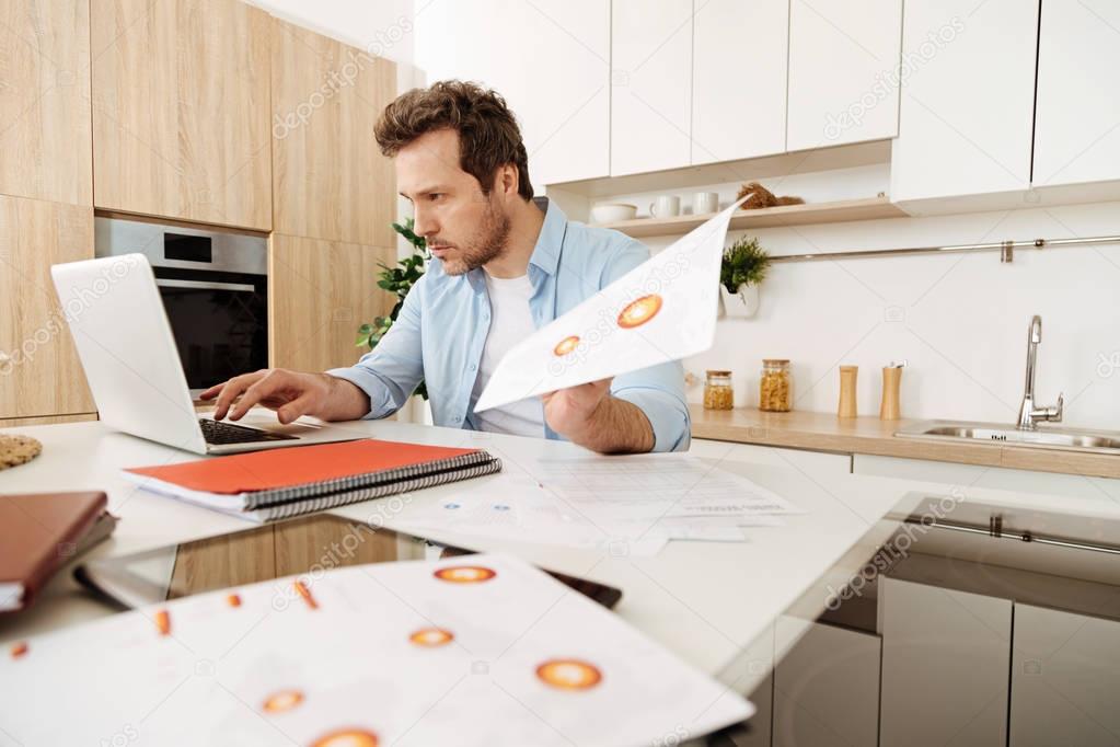 Concentrated man reprinting information from printouts