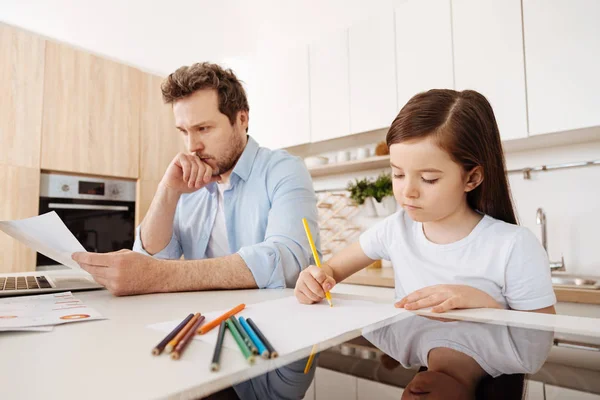 Girl drawing next to her working father — Stock Photo, Image