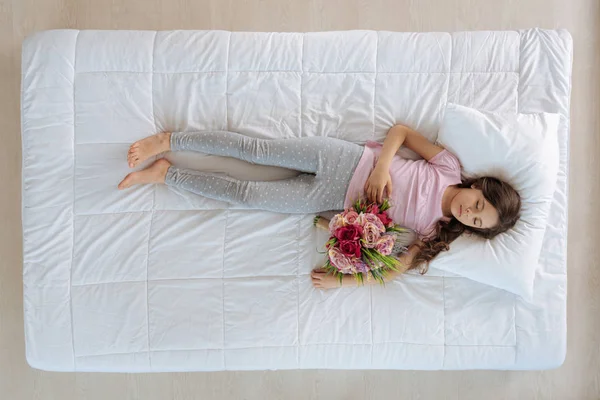 Mädchen schläft und hält Blumen — Stockfoto