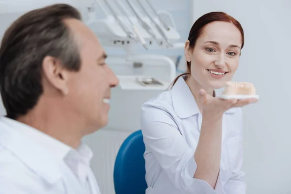 Estagiária feminina segurando dentes artificiais — Fotografia de Stock