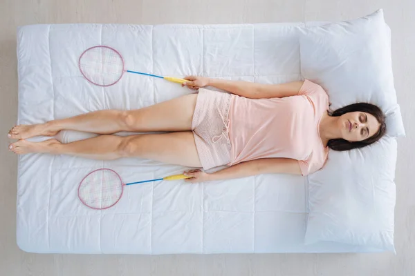 Mujer guapa y agradable durmiendo con raquetas de bádminton —  Fotos de Stock