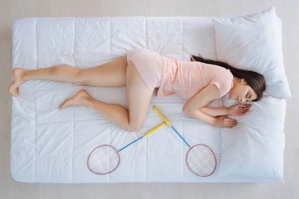 Очаровательная красивая женщина спит рядом с бадминтонными ракетками — стоковое фото