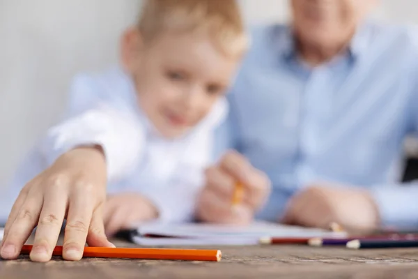 Dolce ragazzo di talento che raggiunge per una matita — Foto Stock