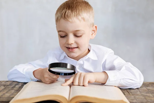 Observant inventive boy using a lens for reading — Stock Photo, Image