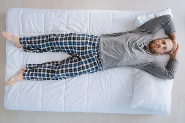 Приятный бородатый мужчина лежит на кровати — стоковое фото