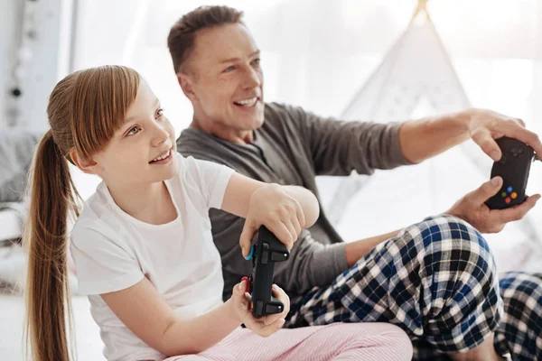 Niño emocional comprometido y su padre usando controladores para jugar — Foto de Stock