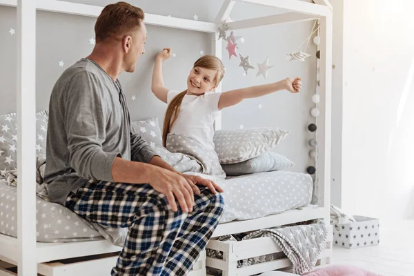Beundringsværdigt aktivt barn strækker sig i hendes seng - Stock-foto