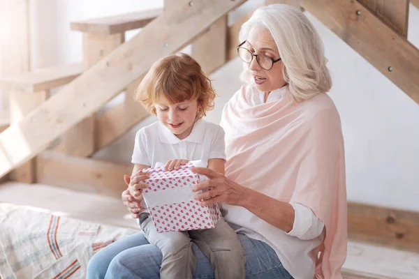 Gledelig nysgjerrig gutt som åpner en gave – stockfoto