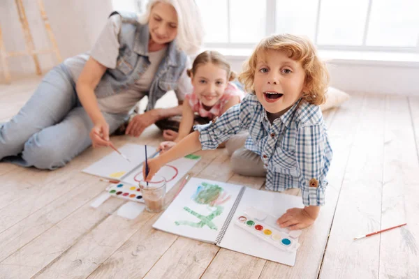 Glad söt pojke att sätta hans målningen borste i vattnet — Stockfoto