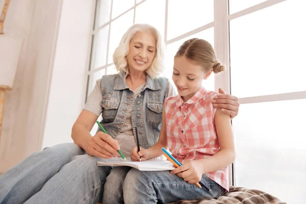 Vrolijke bejaarde vrouw tekenen met haar kleindochter — Stockfoto