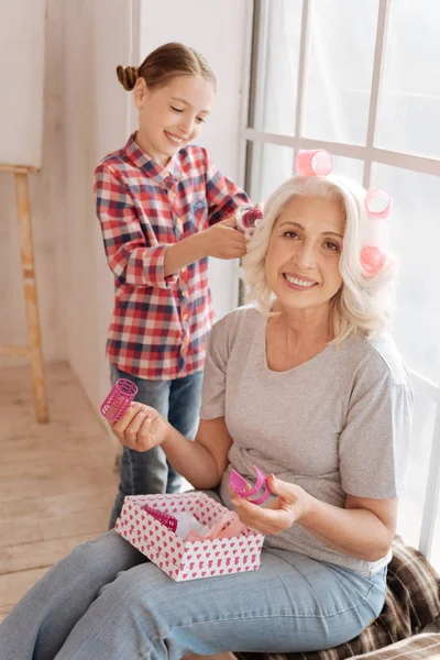 Joyful senior woman holding hair rollers — Stock Photo, Image